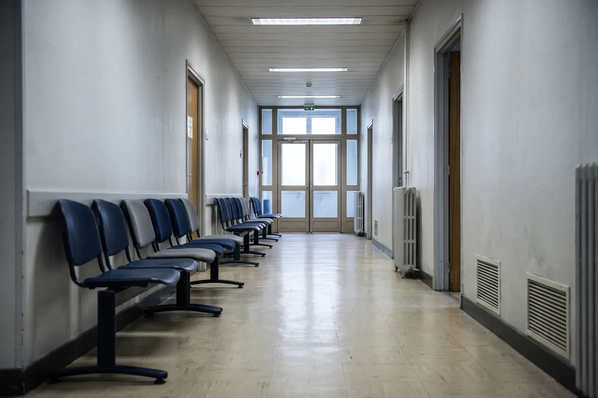 Un couloir vide de bâtiment administratif avec une rangée de chaises : l'attente pendant l'enquête
