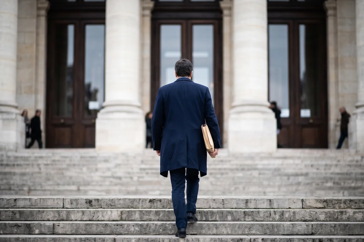 Un homme monte les marches d'un bâtiment public avec son dossier sous le bras : le recours devant le tribunal administratif